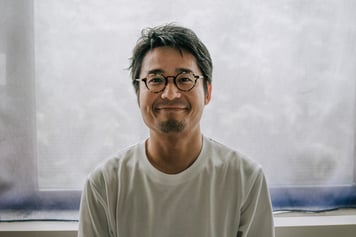 Warmly Smiling Japanese Man Sitting in Soft Backlight at Home stock photo