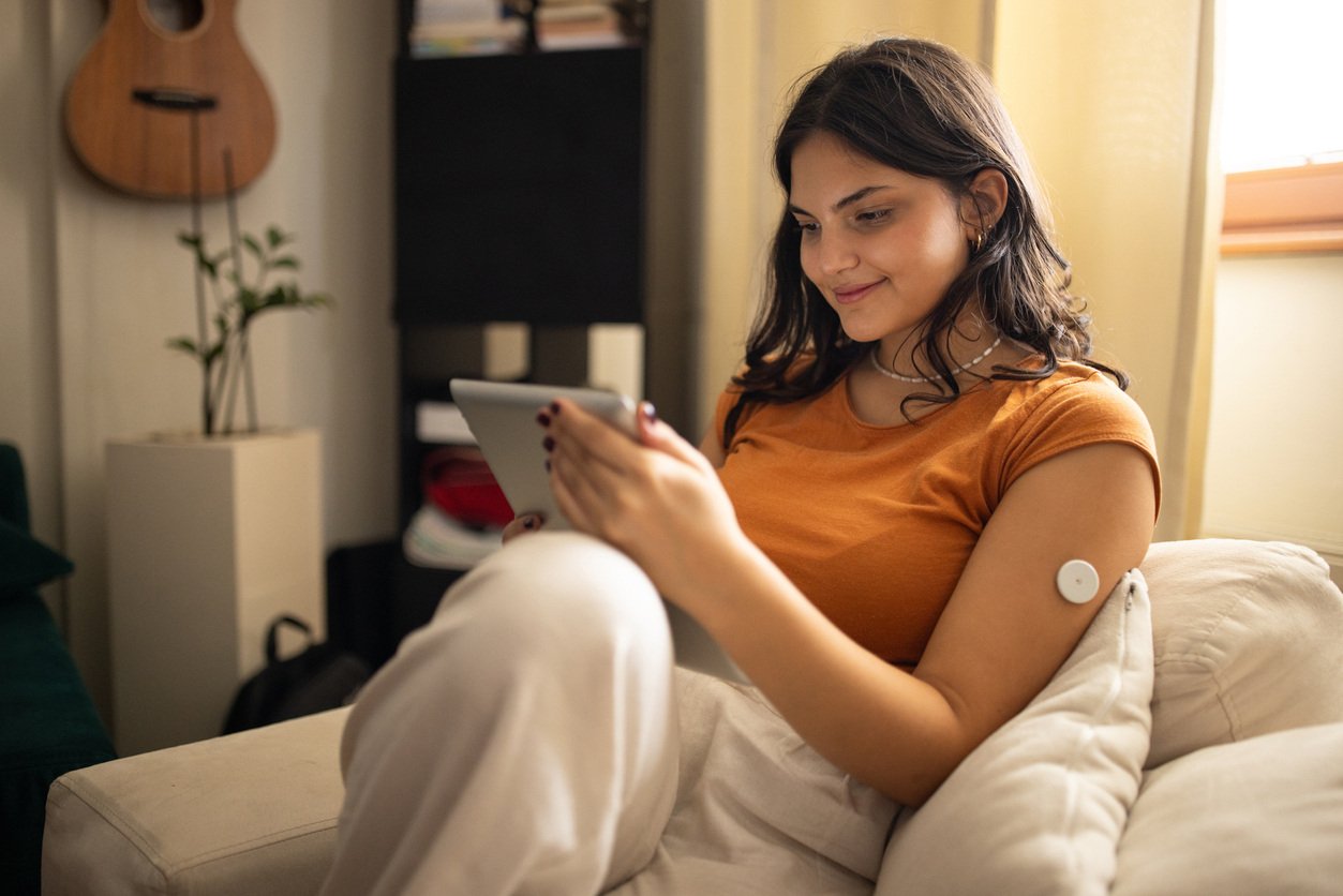 woman with a glucose monitor looking at a tablet